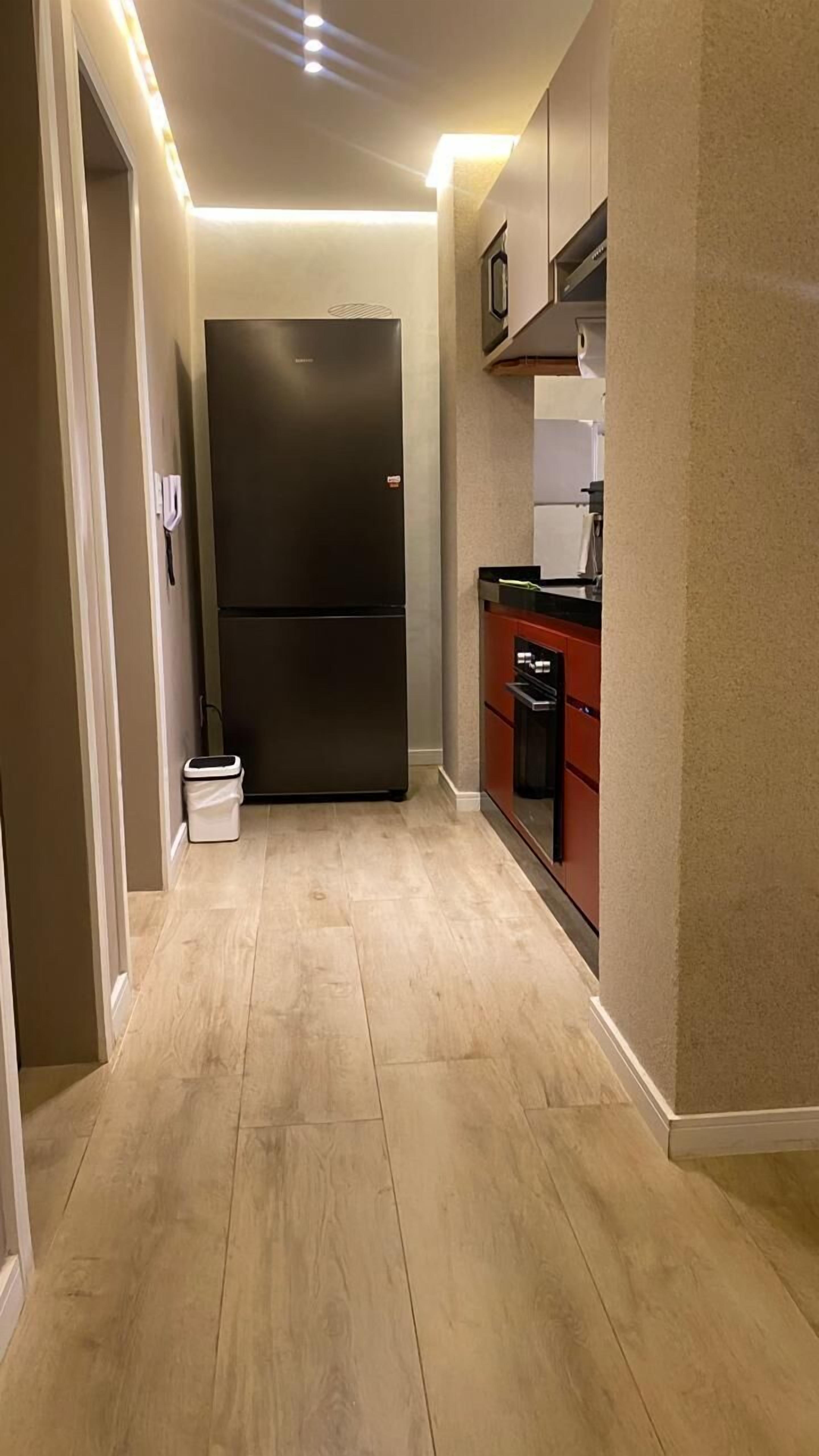 A kitchen with a large black refrigerator, a dishwasher, and a microwave.