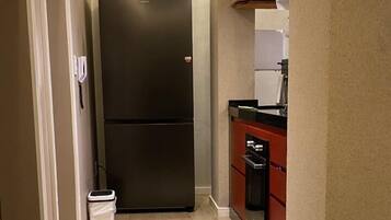 A kitchen with a large black refrigerator, a dishwasher, and a microwave.