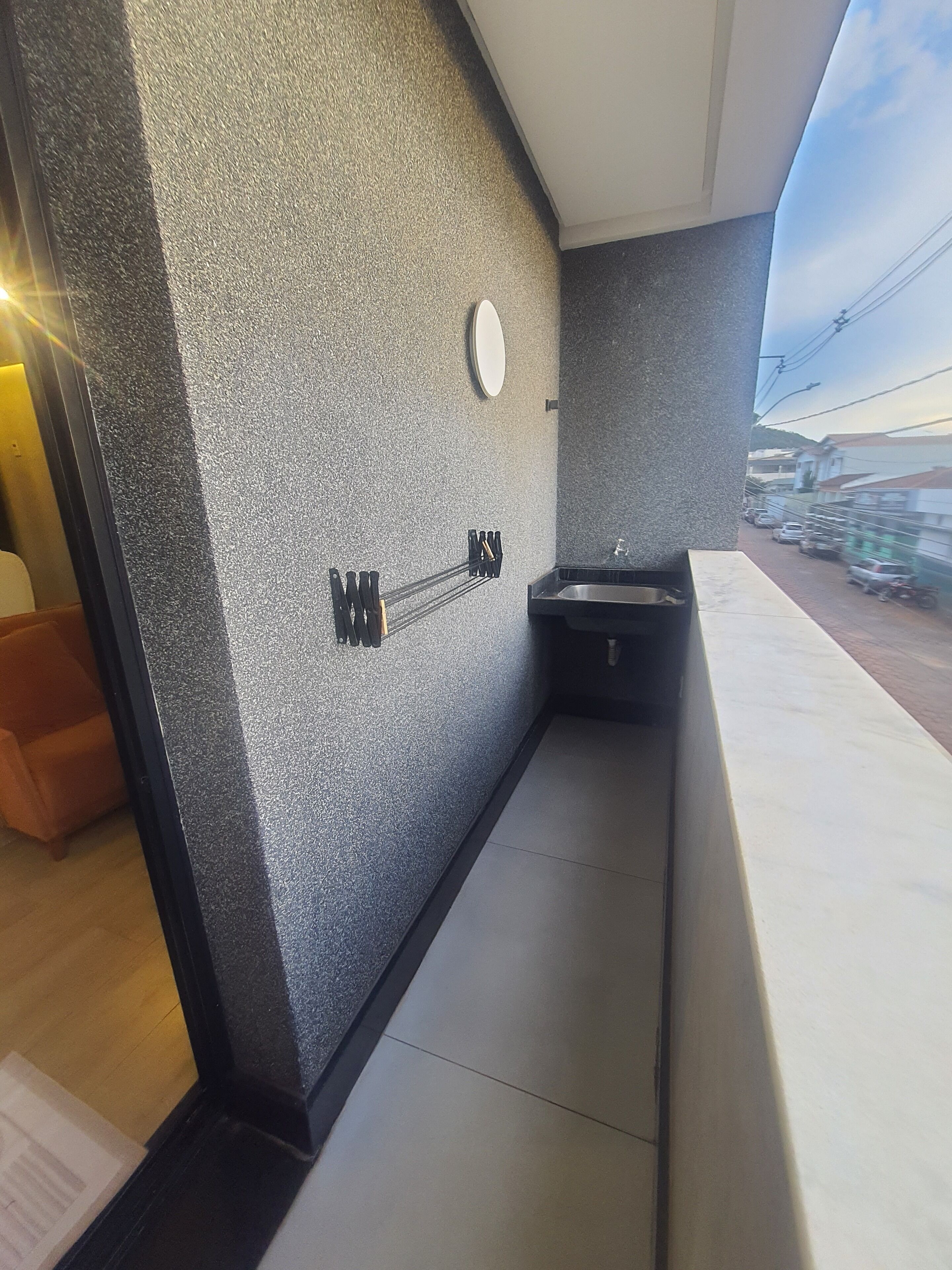A modern bathroom with a grey speckled wall, a round mirror, and a black sink.