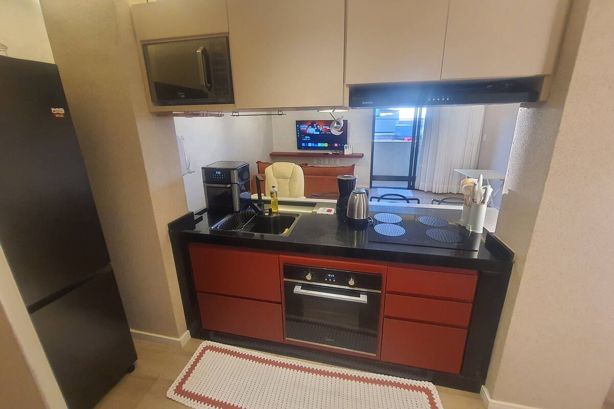 Une cuisine compacte équipée d’un four à micro-ondes, d’une cuisinière et d’un évier.