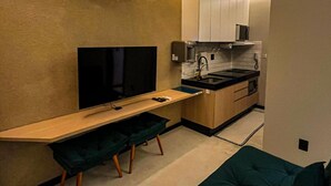 A compact kitchen with a flat-screen TV, a coffee maker, and a microwave. - Apart-hotel Theotókos Flats (Piumhi)