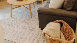 Ein gemütliches Wohnzimmer mit einem dunkelbraunen Sofa, einem runden Holztisch und einem Korbwäschekorb.