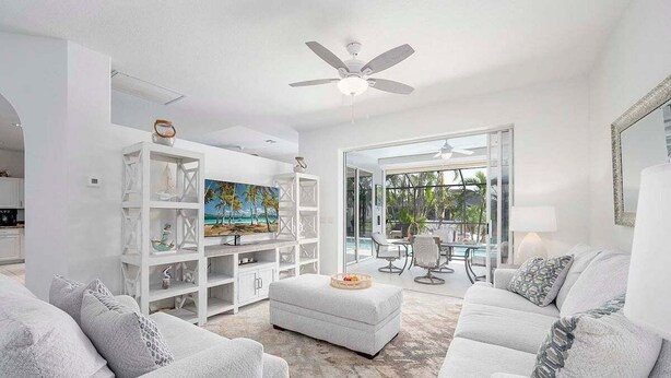 A spacious living room with a white sofa set, a white entertainment unit with shelves, and a large painting. - Flamingo House - with  Boat dock & Kayak & Fenced (Cape Coral)