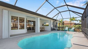 Une piscine dotée d’un patio couvert, attenant à un bâtiment avec de grandes fenêtres et une porte.
