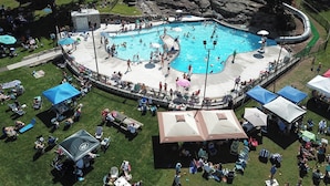 Ein großer Pool im Freien, umgeben von Rasenflächen und Picknicktischen.