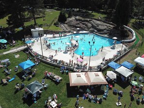 Ein großer Pool im Freien, umgeben von Rasenflächen und Picknicktischen.