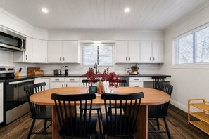 A modern kitchen with white cabinetry, a central island with chairs, and a dining table. - The Spot Lake Wallenpaupack-WLE (Lake Ariel)