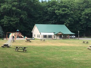 Ein Park mit Picknicktischen, einem Spielplatz und einem Gebäude mit begrüntem Dach.