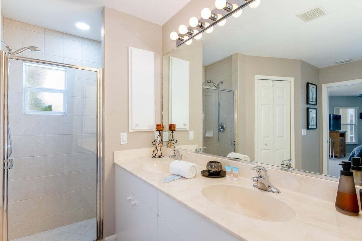 A modern bathroom with a glass-enclosed shower, a large mirror, and a vanity with a sink.