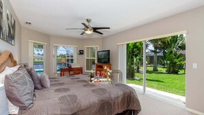 A bedroom with a bed, a television, and a view of the outdoors. - Alecia -Gulf access Home (Cape Coral)
