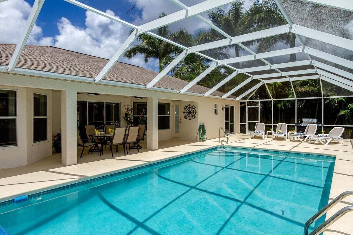 Une piscine dotée d’un espace couvert, de chaises longues et offrant une vue sur les palmiers.