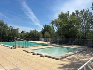 A pool area with two rectangular pools, surrounded by a fence, and shaded by trees. - Cottage with a pool, air conditioning, 2 bedrooms, 2 bathrooms, and secure parking (Velleron)