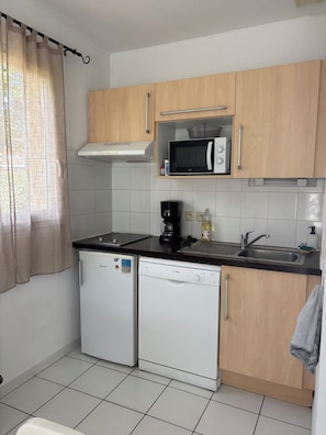 A compact kitchen with a microwave, coffee maker, and dishwasher.