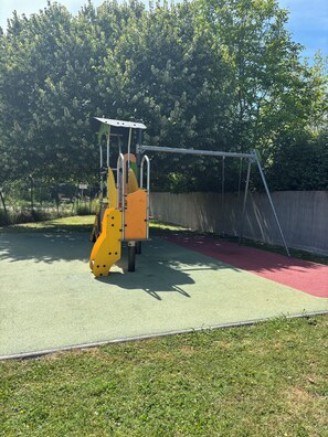 A playground with a yellow climbing structure and a red and green play area.