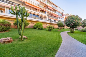 Un hotel de varios pisos con balcones, un césped cuidado y un camino pavimentado.