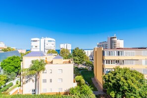 A residential area with modern buildings, a clear blue sky, and a view of the sea.