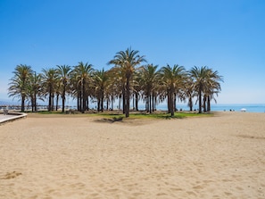 Una playa arenosa con palmeras y cielo despejado.