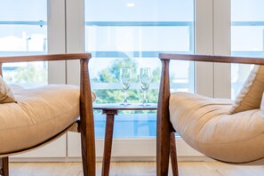 Dos sillas de madera con cojines, una mesita y dos vasos de agua.
