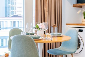 A dining area with a round table, two chairs, a vase with flowers, and a glass container.