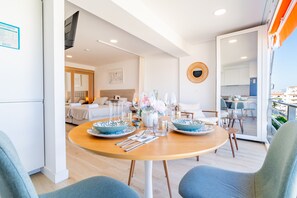A dining area with a round table, chairs, and a view of the kitchen and living room.