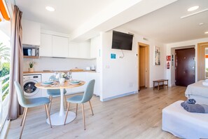 A modern apartment with a dining area, kitchen, living room, and a door leading to another room.