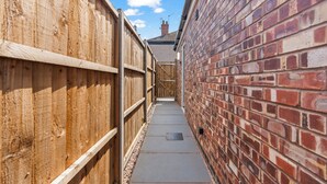 A narrow alleyway with wooden fences on one side and a brick wall on the other. - City Centre House with EV Parking  (Coventry)