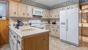 A kitchen with wooden cabinets, a white refrigerator, a microwave, and a sink.