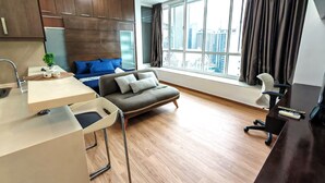 Un apartamento moderno con kitchenette, un sofá, una mesa de comedor y un ventanal con vistas a la ciudad.