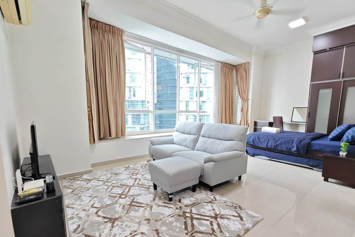 A modern living room with a sofa, a TV, and a large window with curtains.