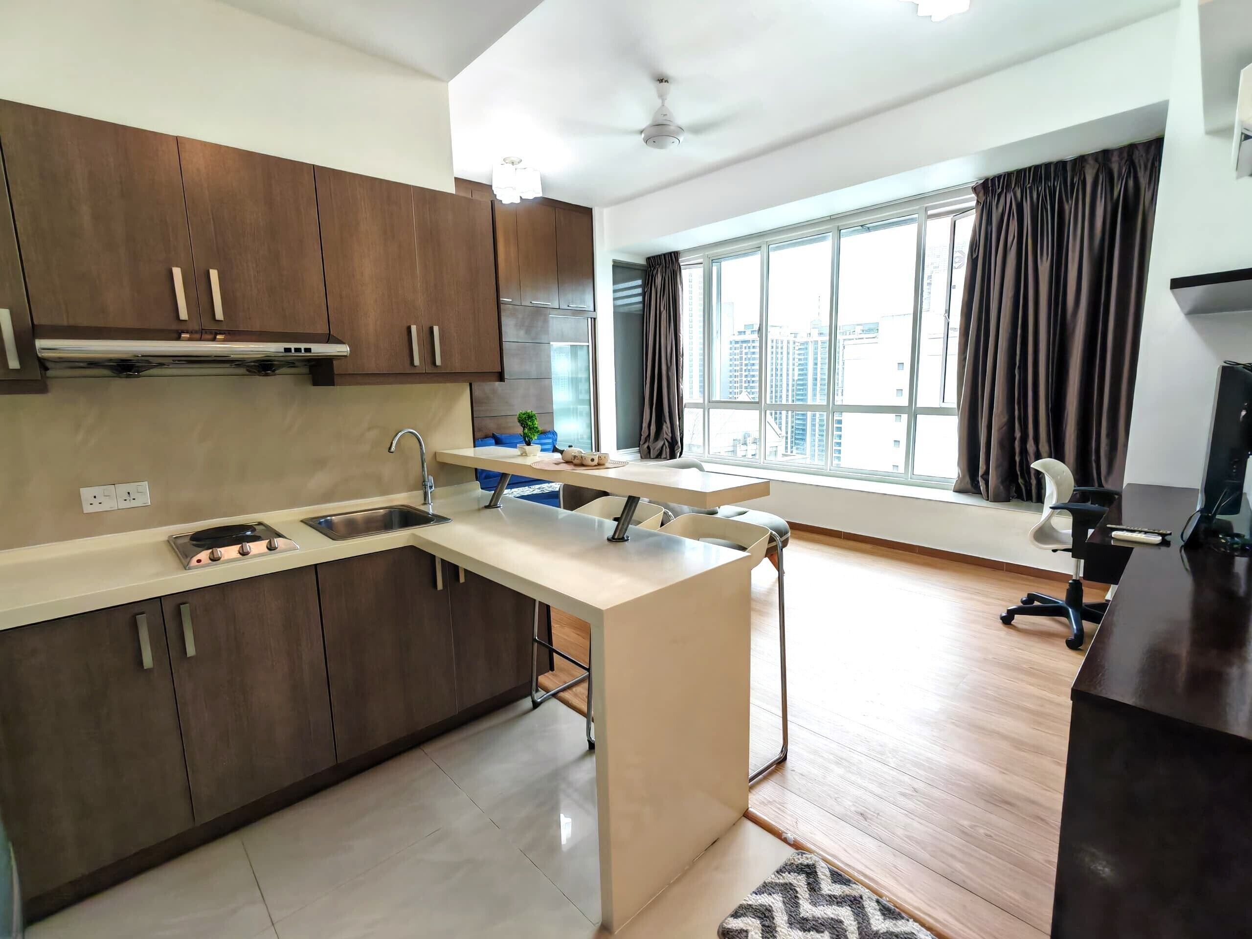 Una cocina moderna con una isla integrada, un ventanal con cortinas y vistas a la ciudad.