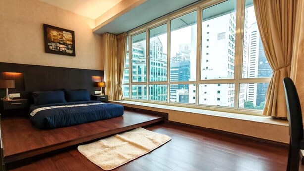Un dormitorio moderno con un ventanal grande, una cama con ropa de cama oscura, una mesita de noche y una alfombra mullida.