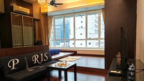 A modern living room with a sofa labeled "PARIS," a coffee table, a TV, and a large window with a city view.