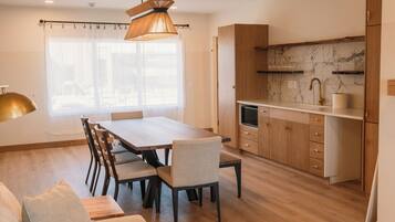 A modern kitchen with wooden cabinets, a marble backsplash, and a dining area with a wooden table and chairs.