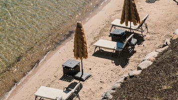 Relax on the beach with comfortable sun loungers and umbrellas, offering a view of the sea.