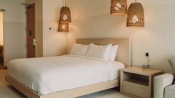 Een hotelkamer met een bed, nachtkastjes en twee hangende rieten lampen.