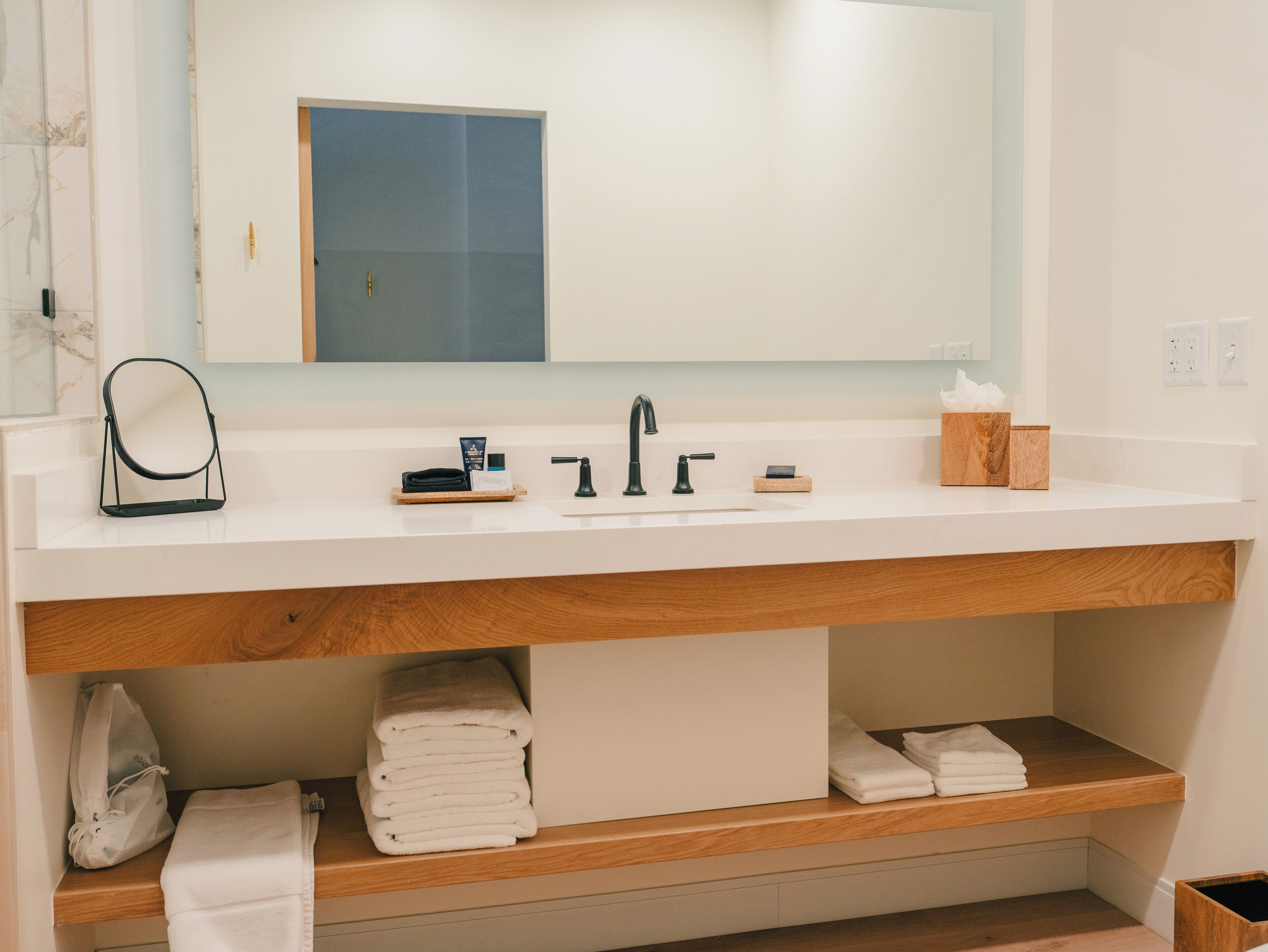Une salle de bain moderne avec un lavabo blanc, un robinet noir et un meuble-lavabo en bois.