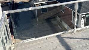 Terraza en la azotea con vista al océano, una bandera y un edificio con el número 206.