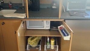 Una cocina con gabinetes de madera, microondas, cafetera y licuadora.