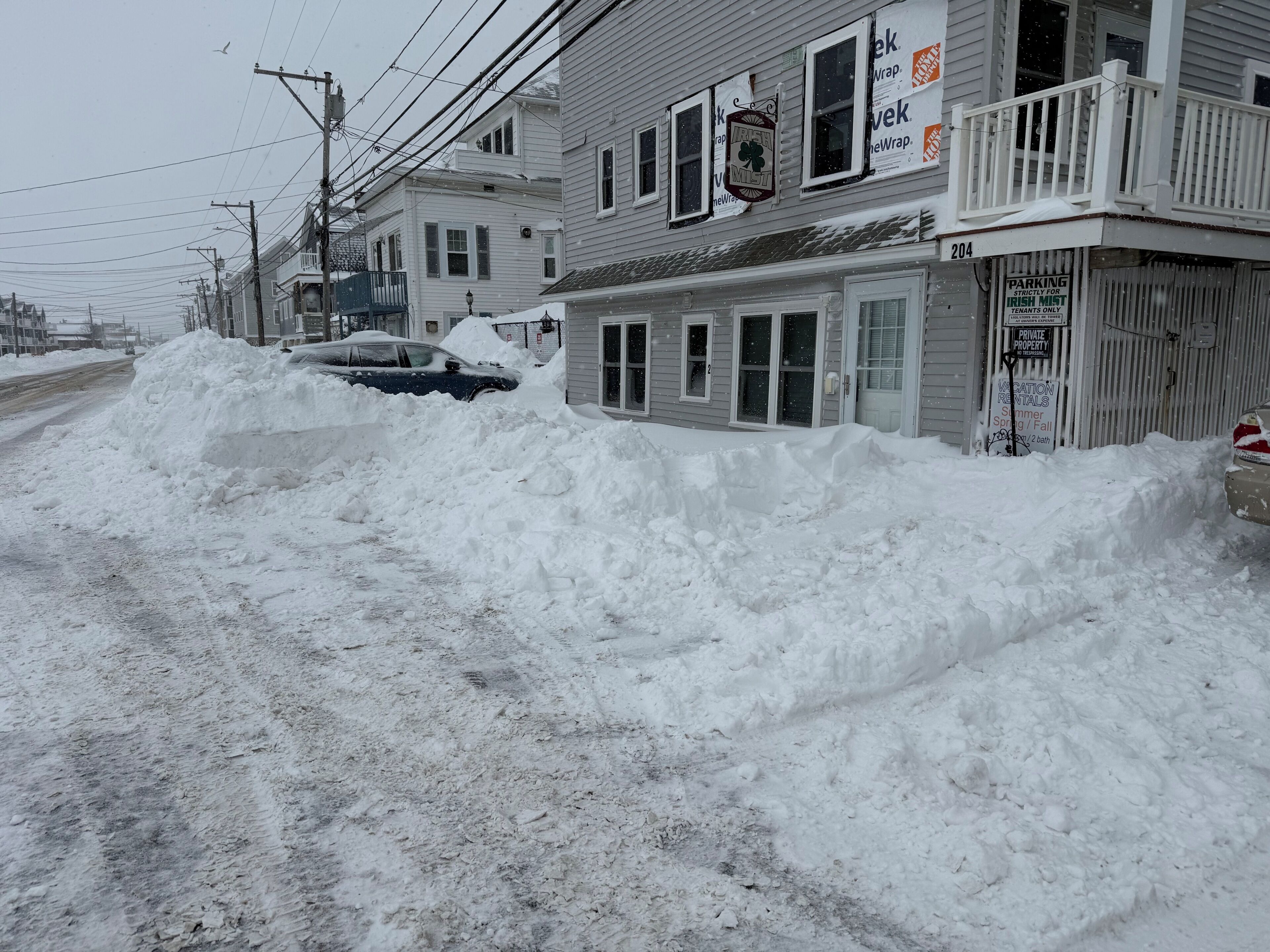 Rua residencial com casas, um monte de neve e uma placa indicando vaga de estacionamento exclusiva para moradores da Irish Mist.