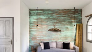 A modern living room with a grey sofa, wooden coffee table, and a rustic wall with a hanging branch decoration. - Naxian Downtown Residence (Naxos Chora)