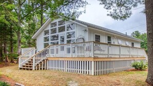 A white house with a deck, surrounded by trees. - Charming Cottage on the Great Pond in Boothbay Harbor, Maine (Boothbay Harbor)