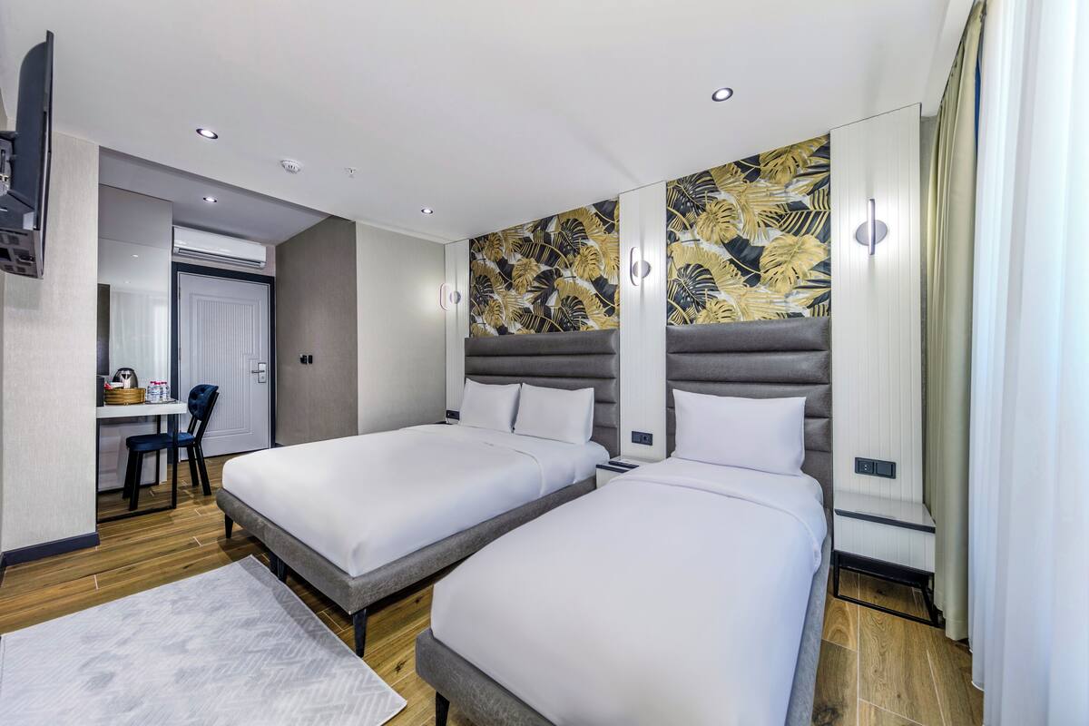 A hotel room with two beds, a desk, and a chair.
