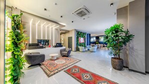 A modern hotel lobby with a reception desk, seating area, and a large potted plant. - Dedem Hotel Premium Çorlu (Corlu)