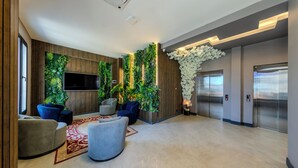A modern lobby with a large TV, seating area, and a wall with vertical gardens. - Dedem Hotel Premium Çorlu (Corlu)