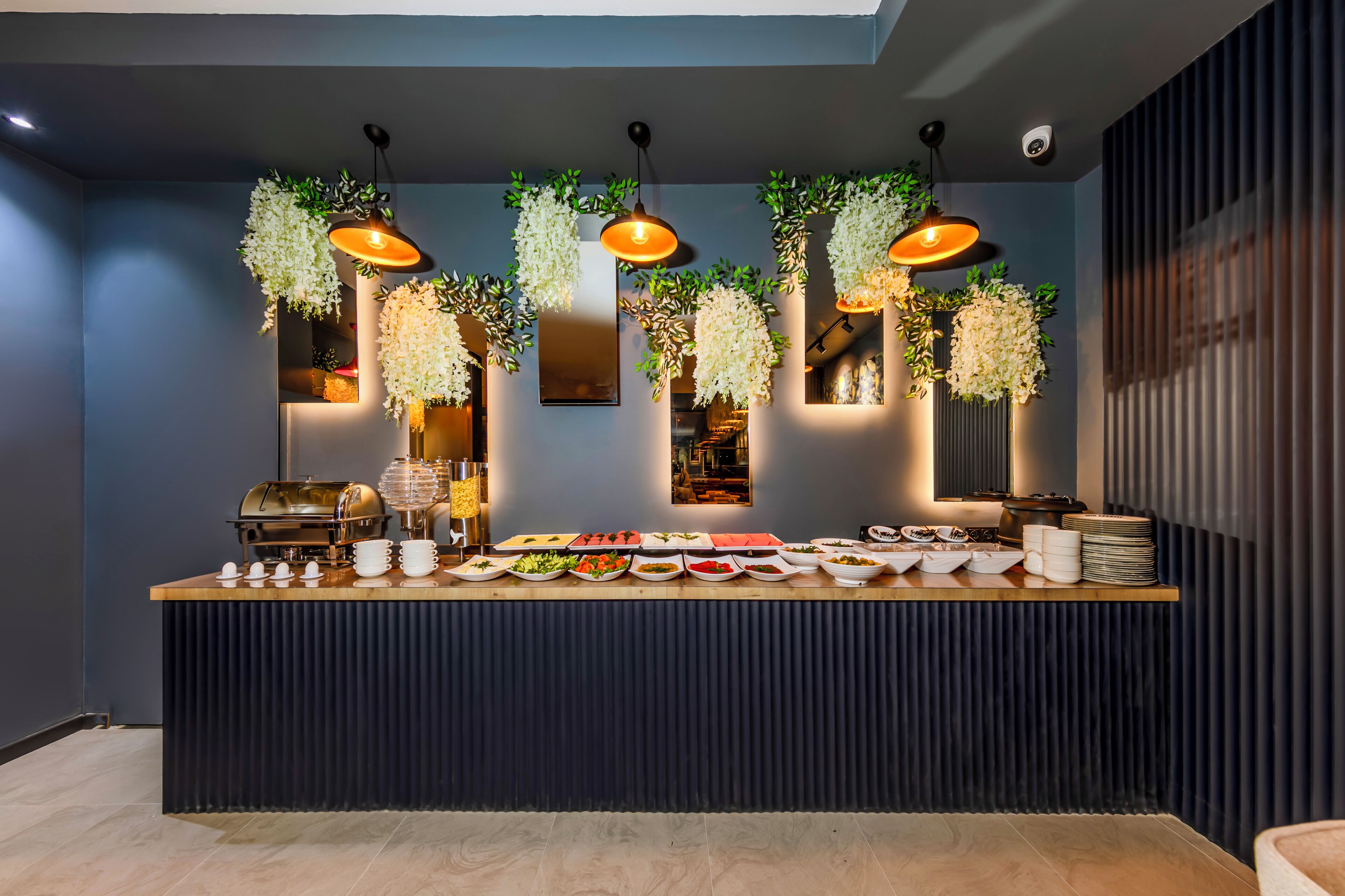 A buffet setup with hanging plants, a coffee station, and various food dishes.