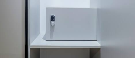A minimalist room with a built-in safe and a small shelf.