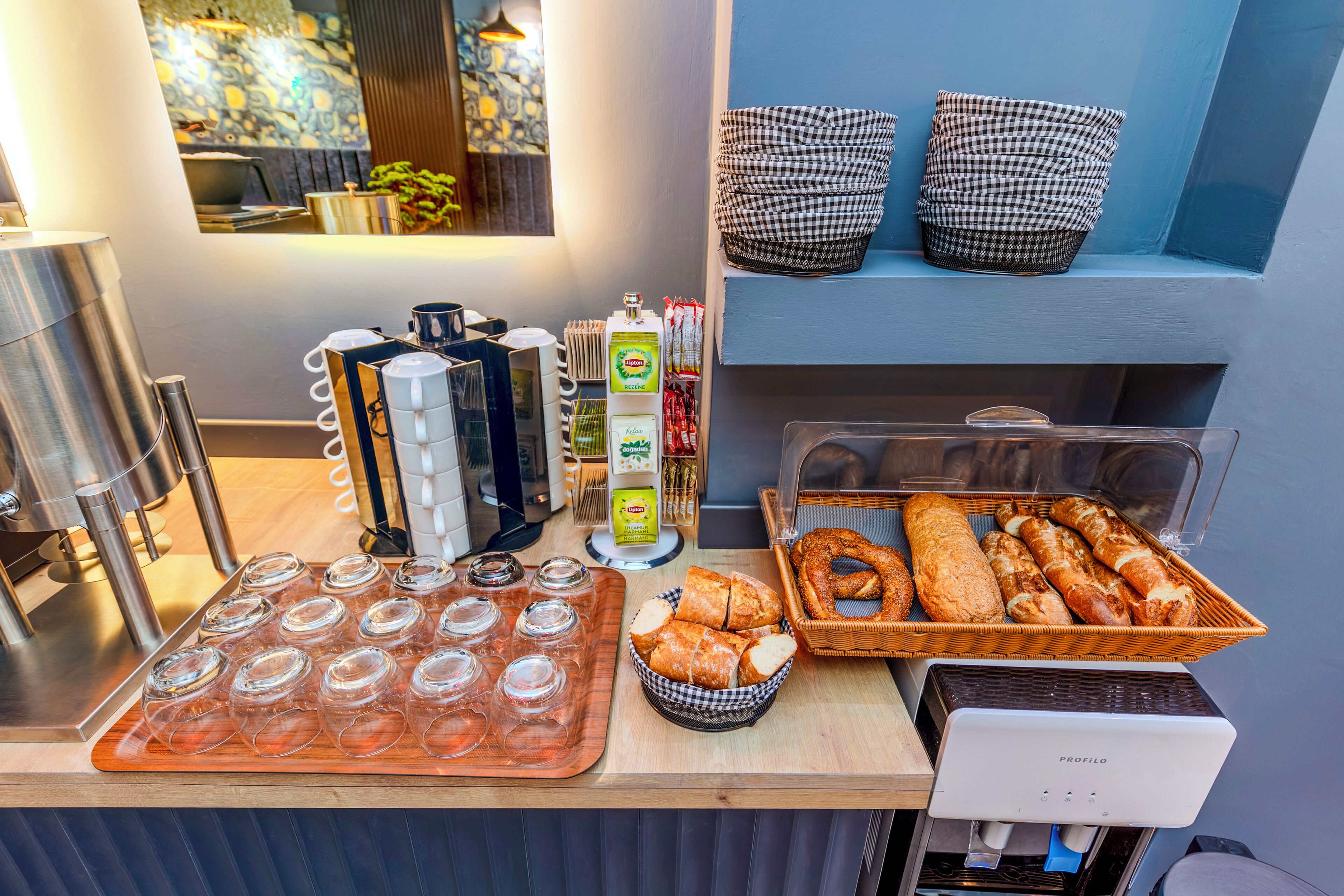 A breakfast bar with a coffee machine, jars of condiments, and a basket of bread.