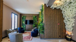 A modern lobby with a flat-screen TV, comfortable seating, a red patterned rug, and vertical gardens. - Dedem Hotel Premium Çorlu (Corlu)