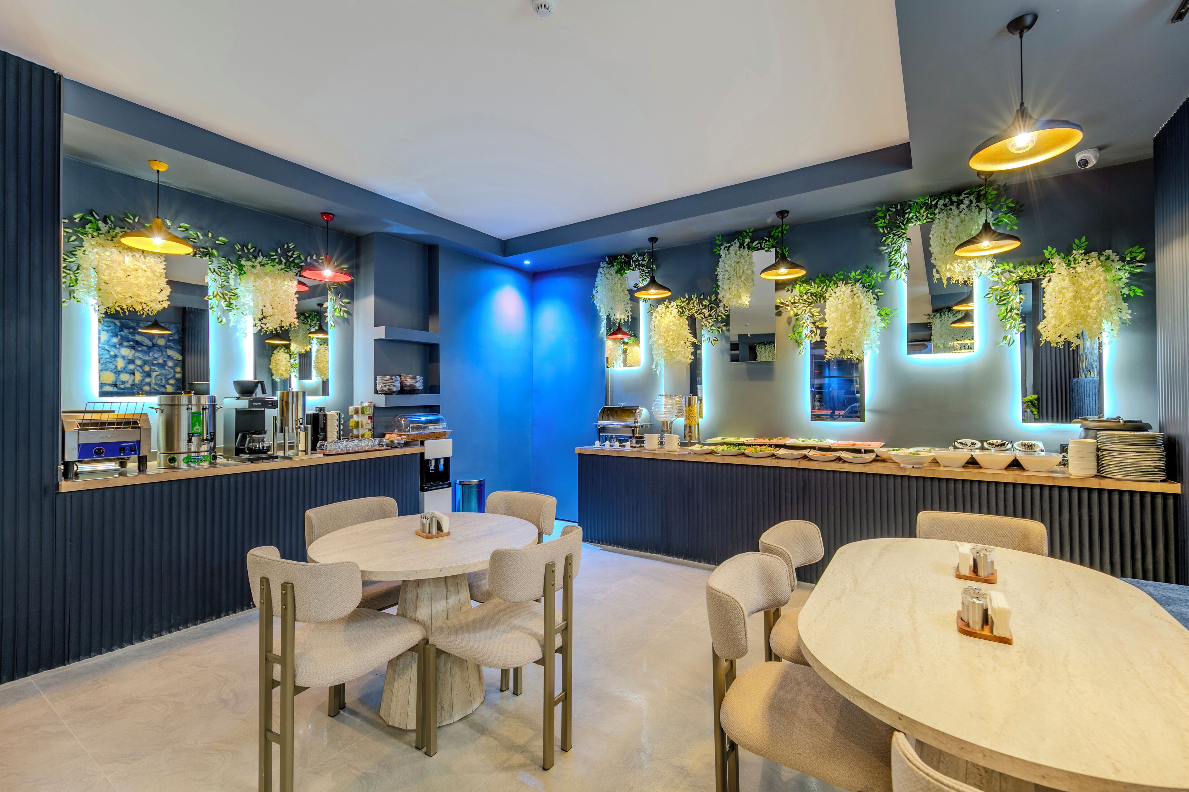 A modern restaurant with round tables and chairs, a bar area, and hanging plants.