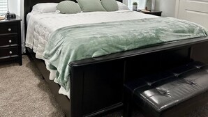 Une chambre à coucher avec un lit, une table de chevet, une lampe et un tableau au mur.